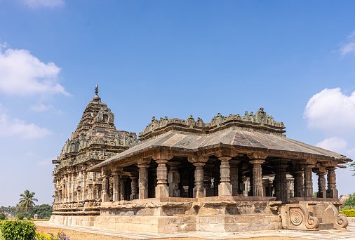 Lakkundi, Karnataka, India - November 6, 2013: Mandapa, entry to brown stone Brahma Jinalaya temple under blue cloudscape in green park.