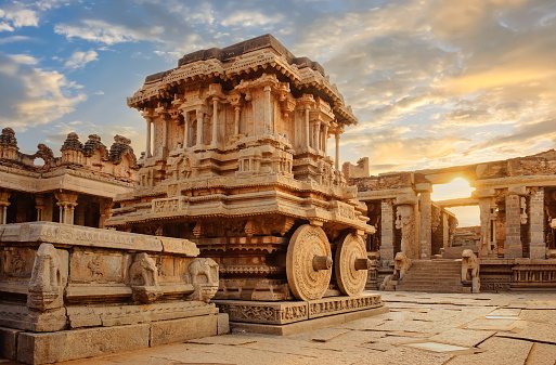 Stone chariot at Hampi with ancient archaeological ruins in the courtyard of Vittala Temple at Karnataka India at sunset