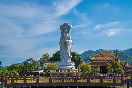 Majestic white Buddha statue on blue sky background. The Lady Buddha (the Bodhisattva of Mercy) at the Buu Lam Tu Pagoda which attracts tourists to visit spiritually on weekends in Vung Tau, Vietnam