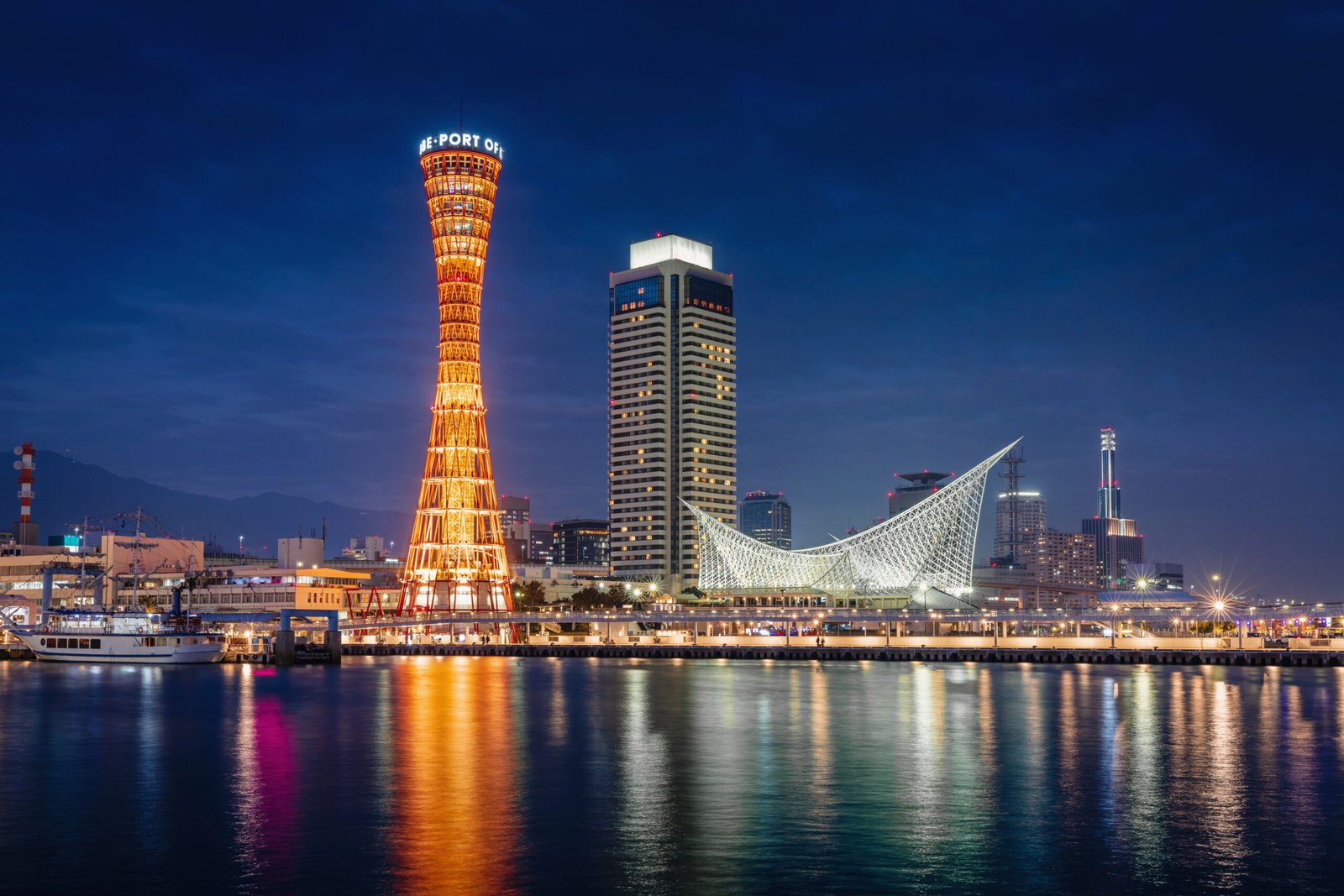 Beautiful illuminated Kobe Port Waterfront Refelections and Harbour Cityscape with orange illuminated Kobe Port Tower at Night after Sunset. Kobe, Honshu, Japan, Asia