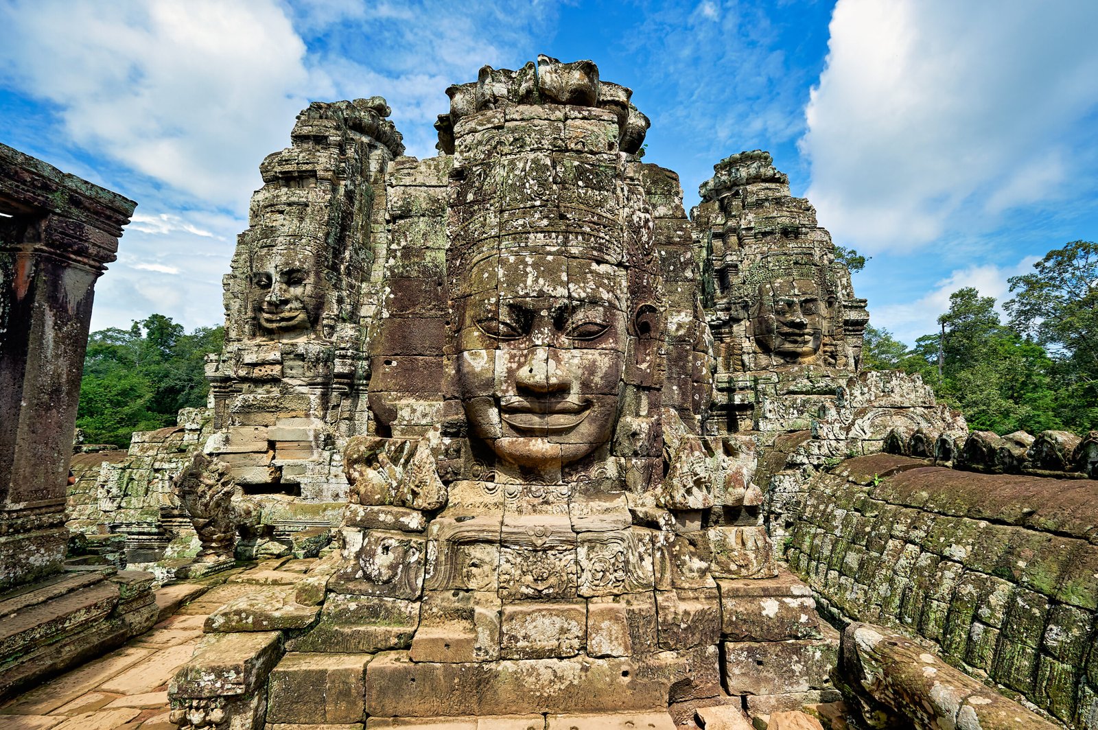 Stone faces of Avalokiteshvara stand tall under the blue sky at Bayon Temple in Angkor Thom, built by King Jayavarman VII.