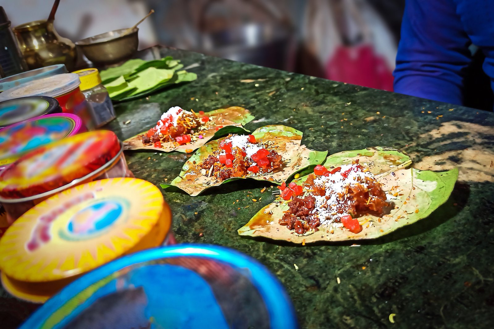 Picture of a famous Banarasi paan shop, showcasing delectable sweet paan adorned with assorted masalas, presented for purchase, with selective focus and a blurred backdrop.